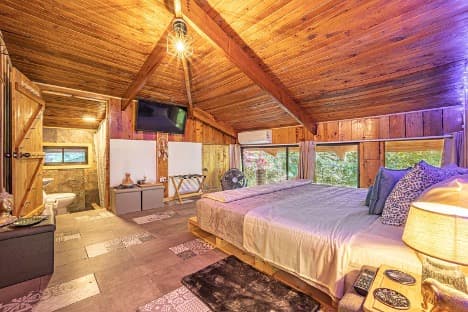 Bright bedroom with natural wood furnishings and a large window overlooking the jungle