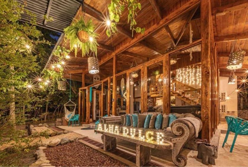 Villa Wanderlust glowing at night with string lights, teal chairs, and inviting outdoor seating