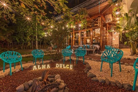 Evening fire circle with teal chairs and warm string lights at Villa Wanderlust