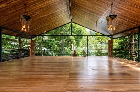 Open-air yoga and gathering platform with vaulted wood ceiling overlooking the jungle
